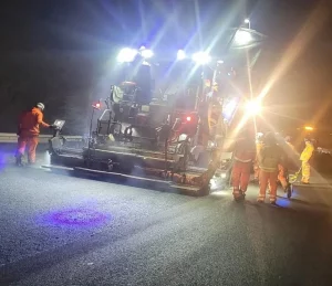 Men resurfacing road at night